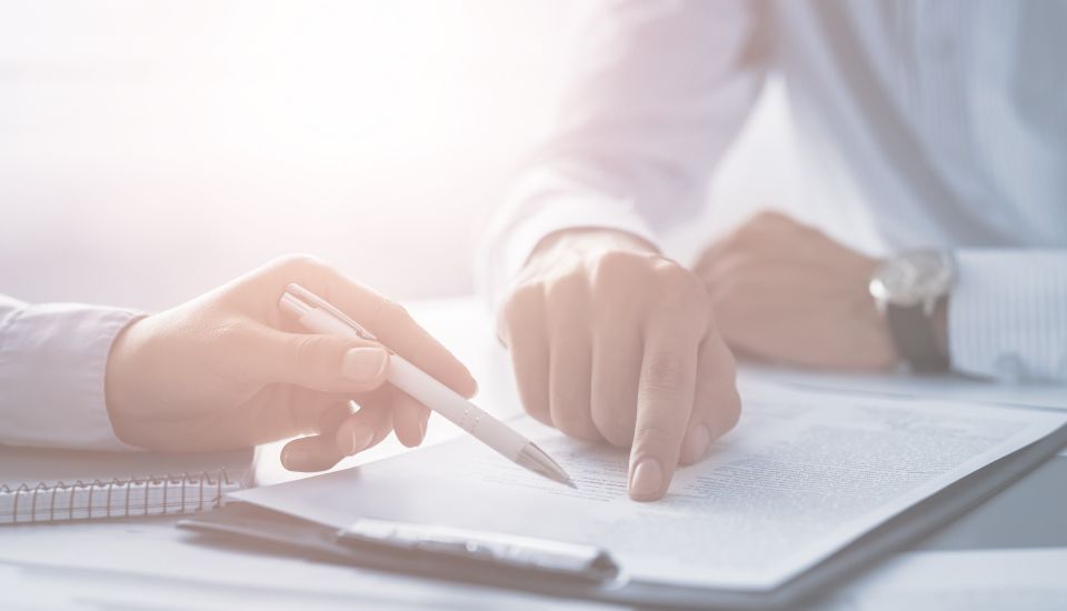 Zwei Personen in Hemden gehen zusammen einen Vertrag durch